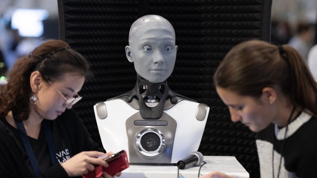 At the All In artificial intelligence conference in Montreal, attendees were seen checking their phones under the watchful gaze of AMECA, an AI robot./Ryan Remiorz captured the scene.