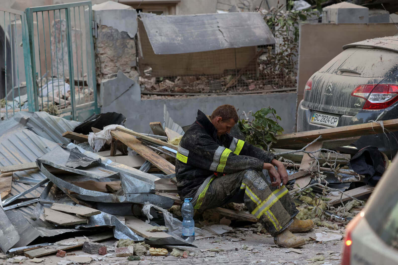 Amidst the ruins of residential buildings targeted by a Russian drone and missile strike, a rescuer pauses for a break.