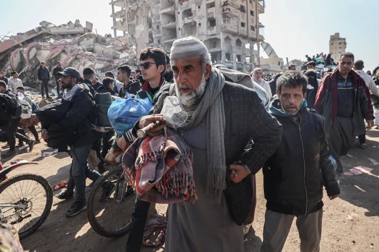 Rifaat Jouda walks with his son as he enters Gaza City following a long journey from southern Gaza,on January 28, 2025 [Abdelhakim Abu Riash/Al Jazeera]